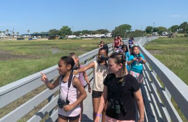 Children walking on a boardwalk over a marsh