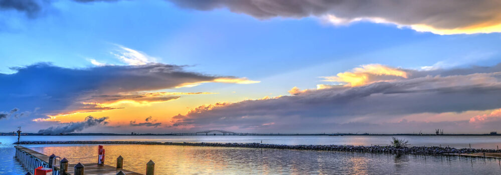 Sunset water scene showing a wooden dock and clouds